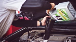 Mechanic adding oil to car engine by Tim Mossholder